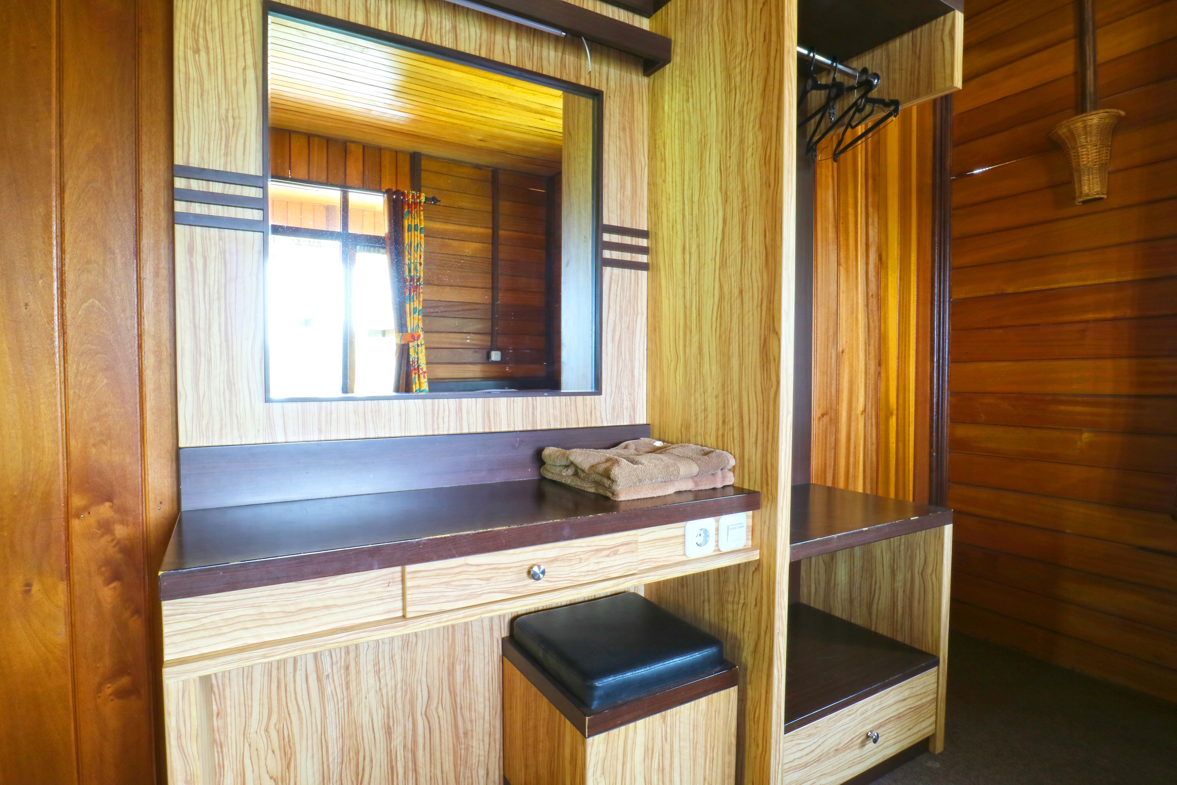 A wooden cabin interior with a mirror, a towel on the counter, and a bench.