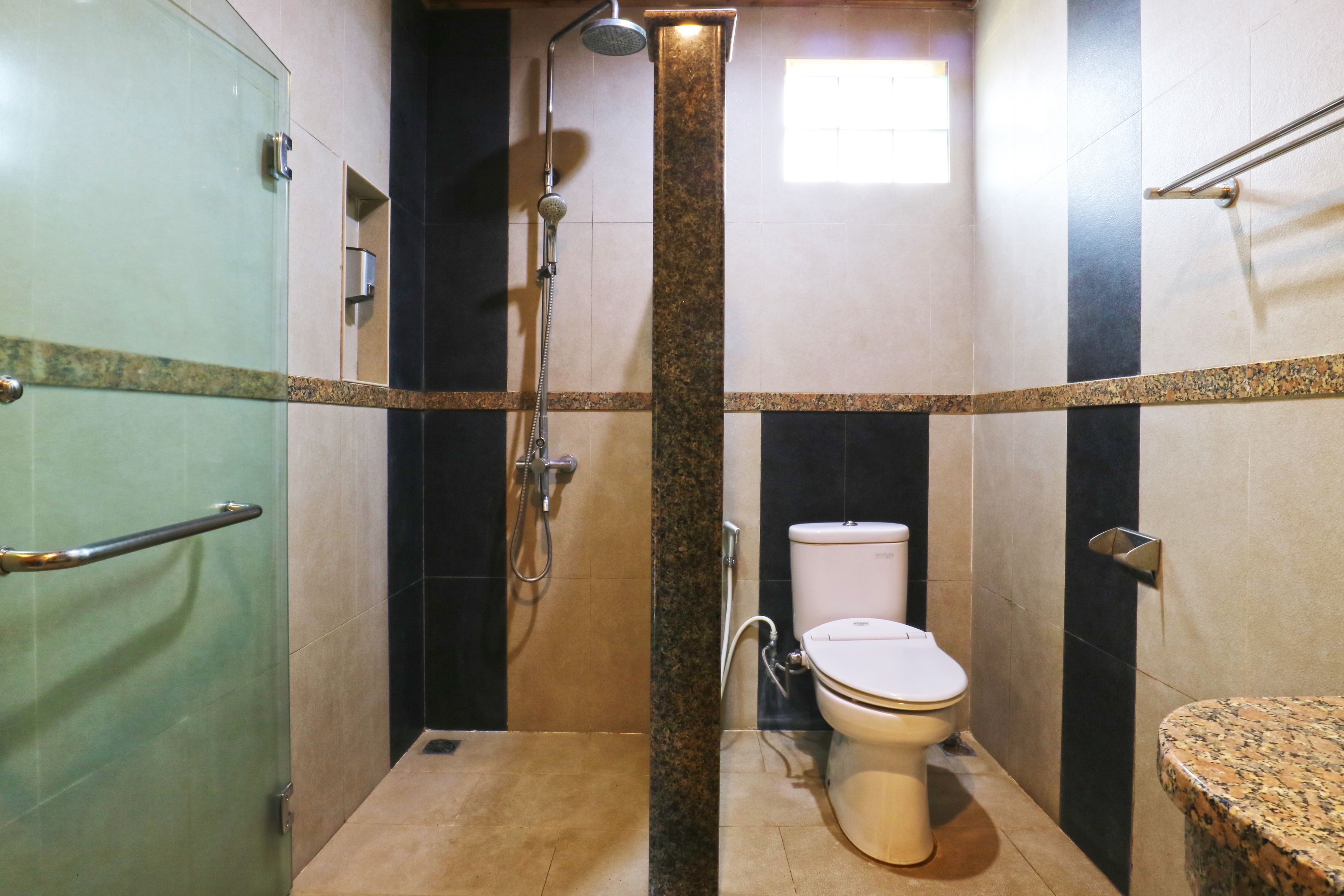 A small, compact bathroom with a glass shower enclosure, a toilet, and a sink.