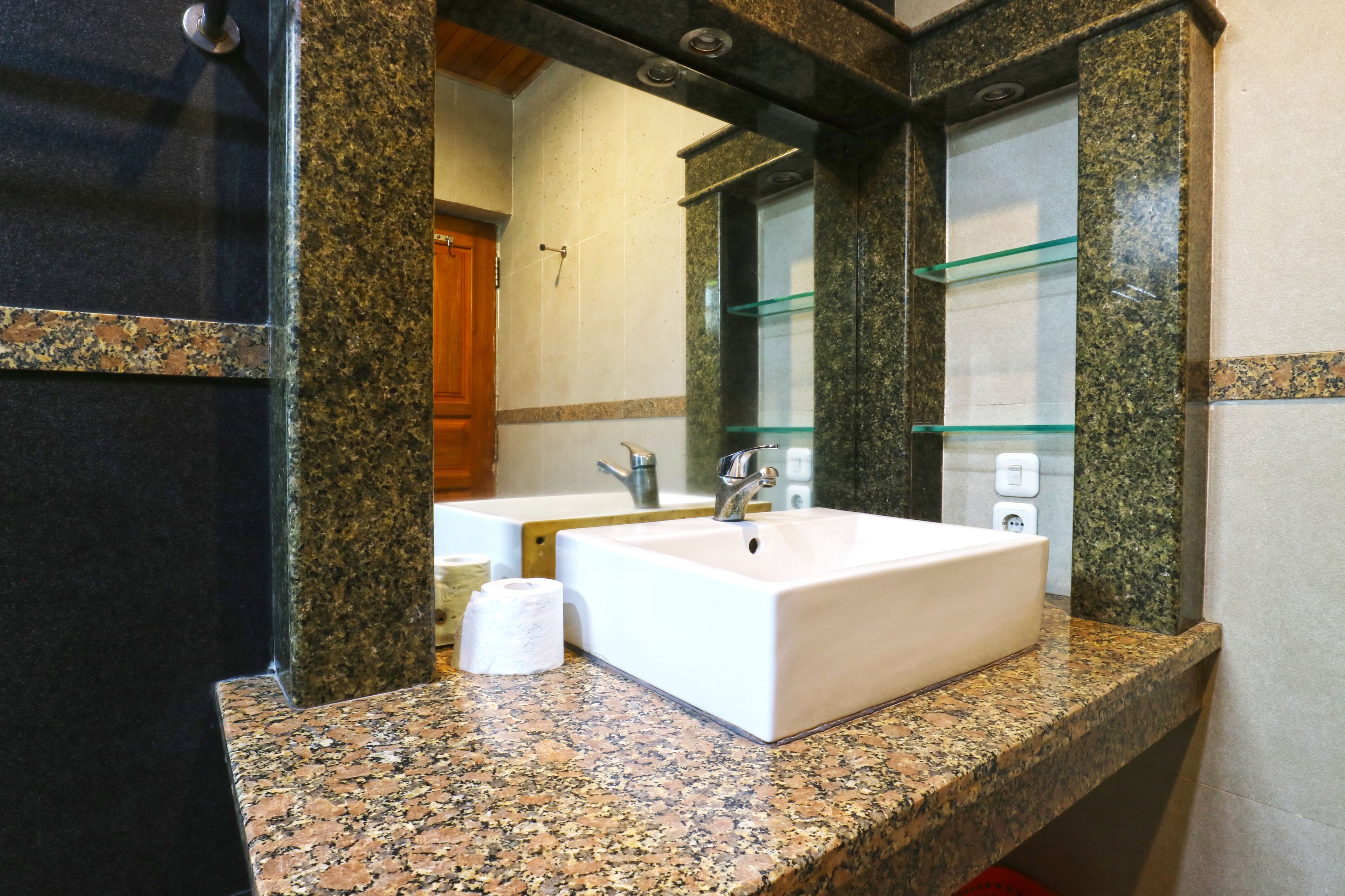 A bathroom with a granite countertop, a white sink, and a mirror.