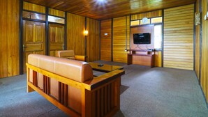 A wooden-paneled room with a leather sofa, a television, and a small table.