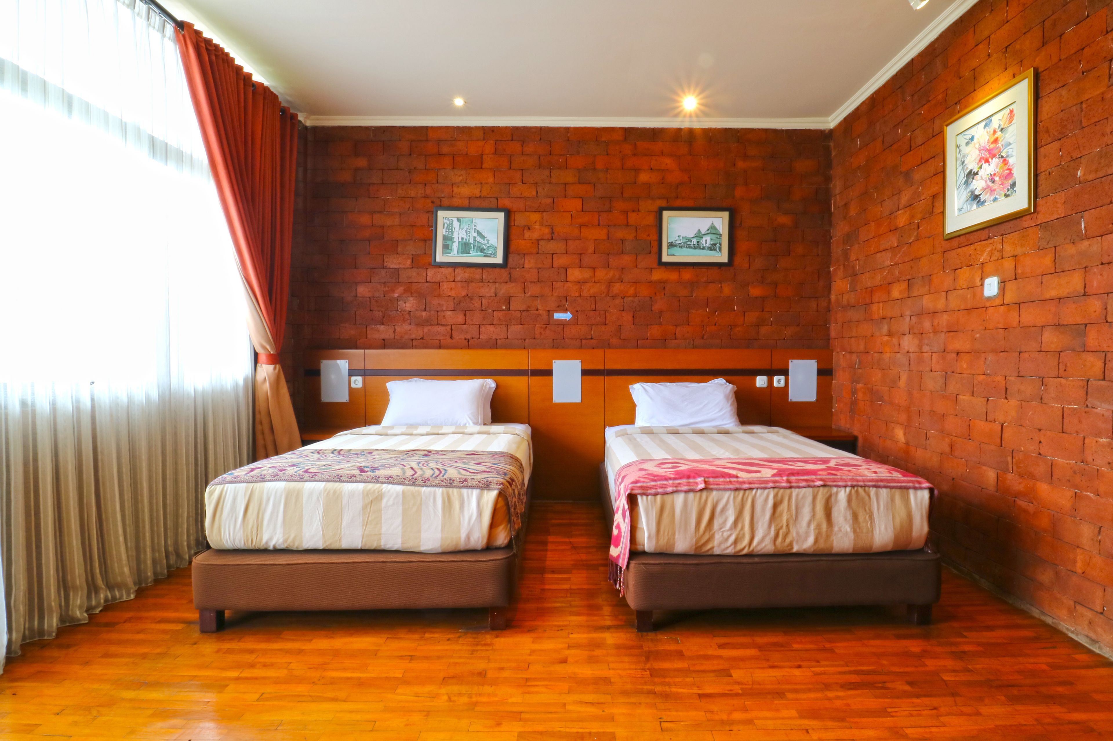Une chambre double avec deux lits, un mur en briques et une fenêtre avec des rideaux.