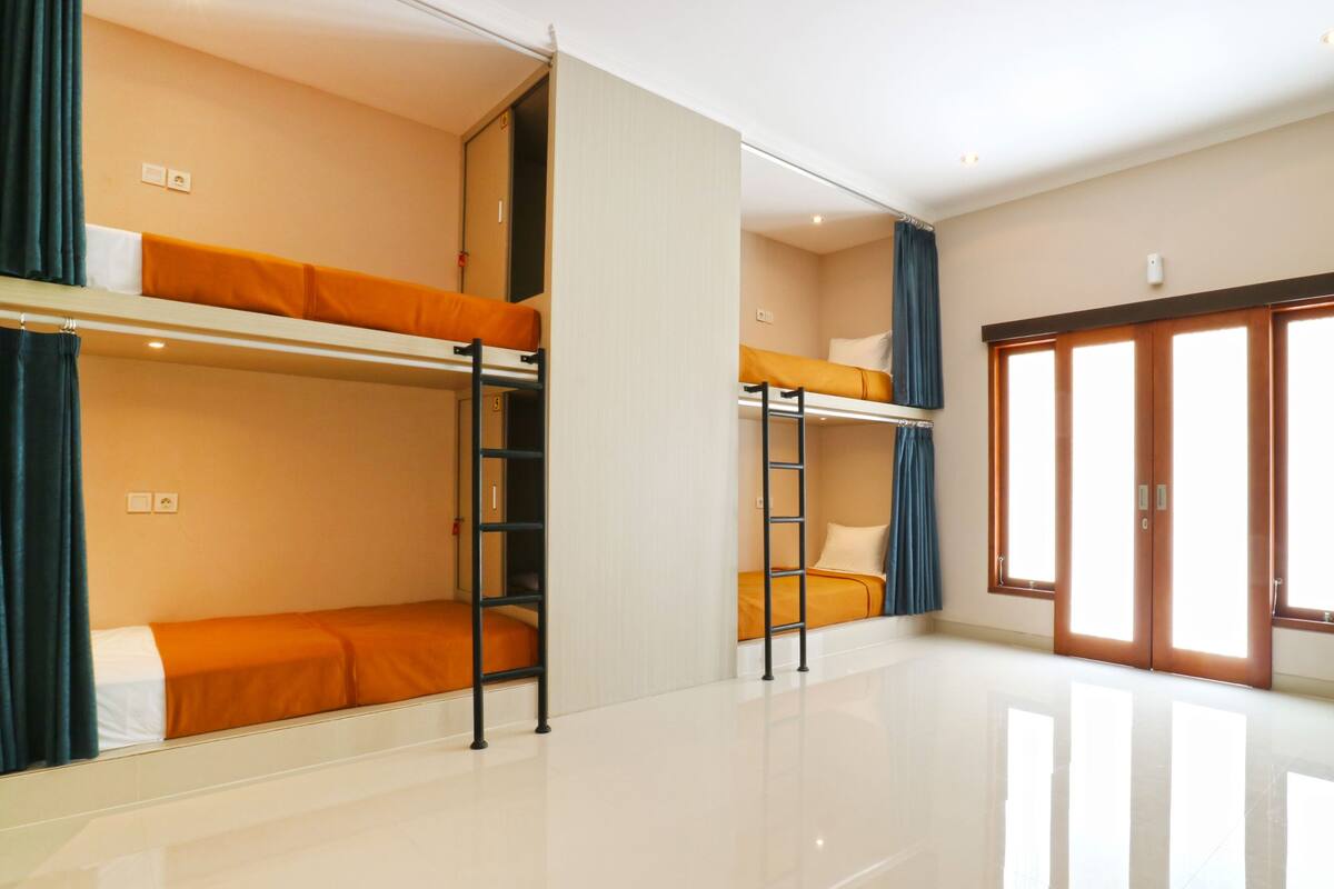 A hotel room with bunk beds, a sliding door, and a large window.