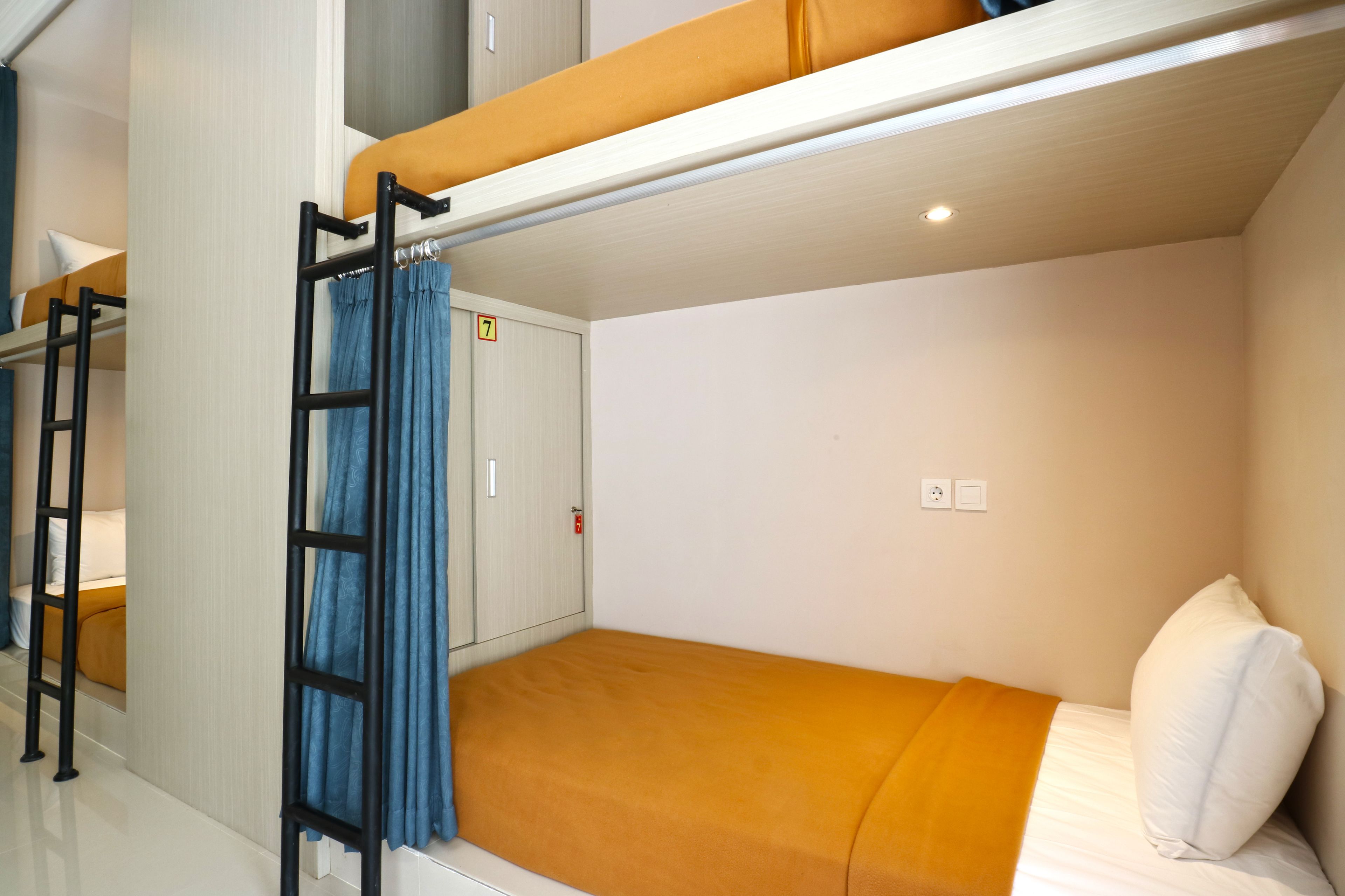 A bunk bed room with a ladder, a door with a number, and a white wall.