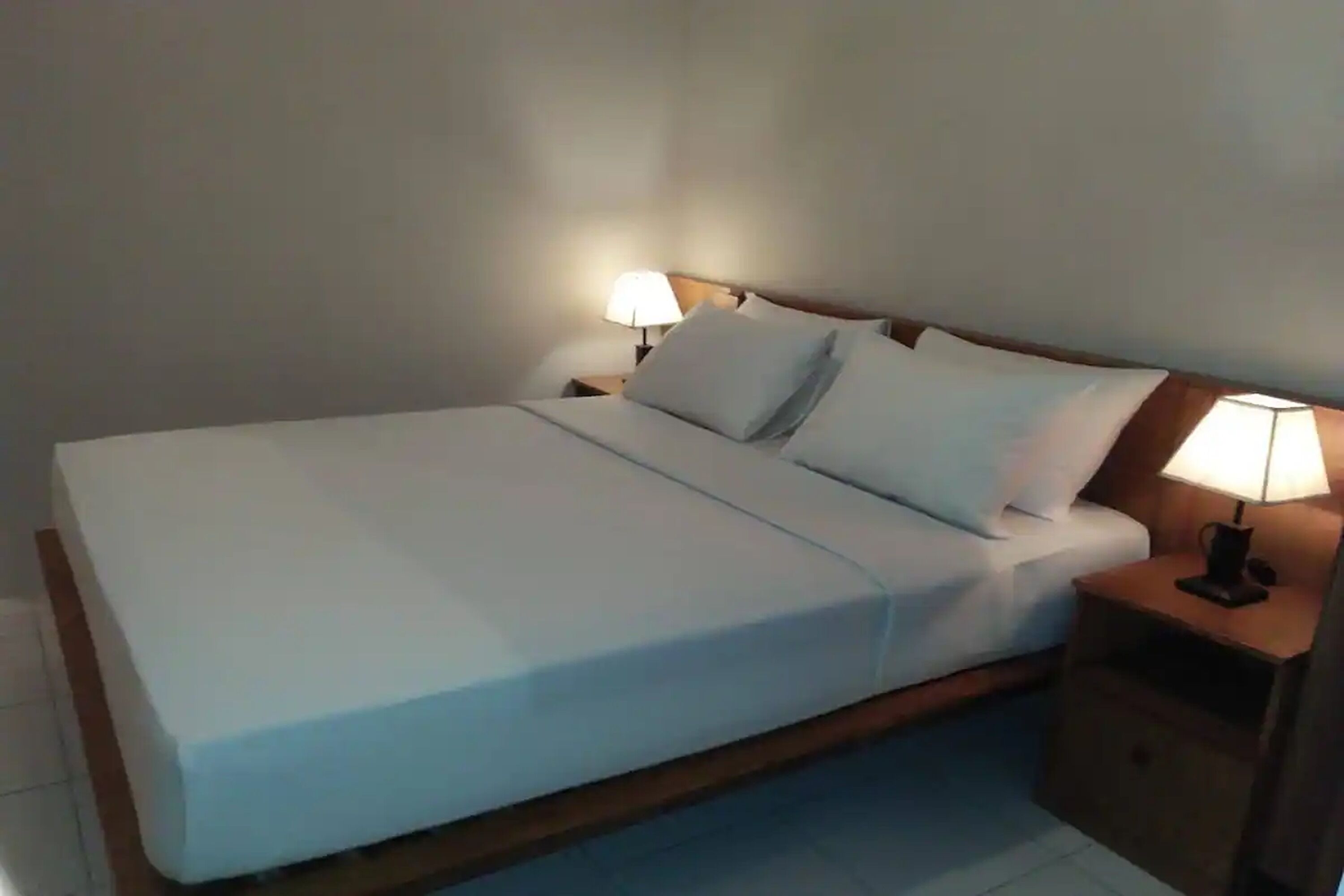 A standard hotel room with a single bed, two bedside tables, and two wall-mounted lamps.