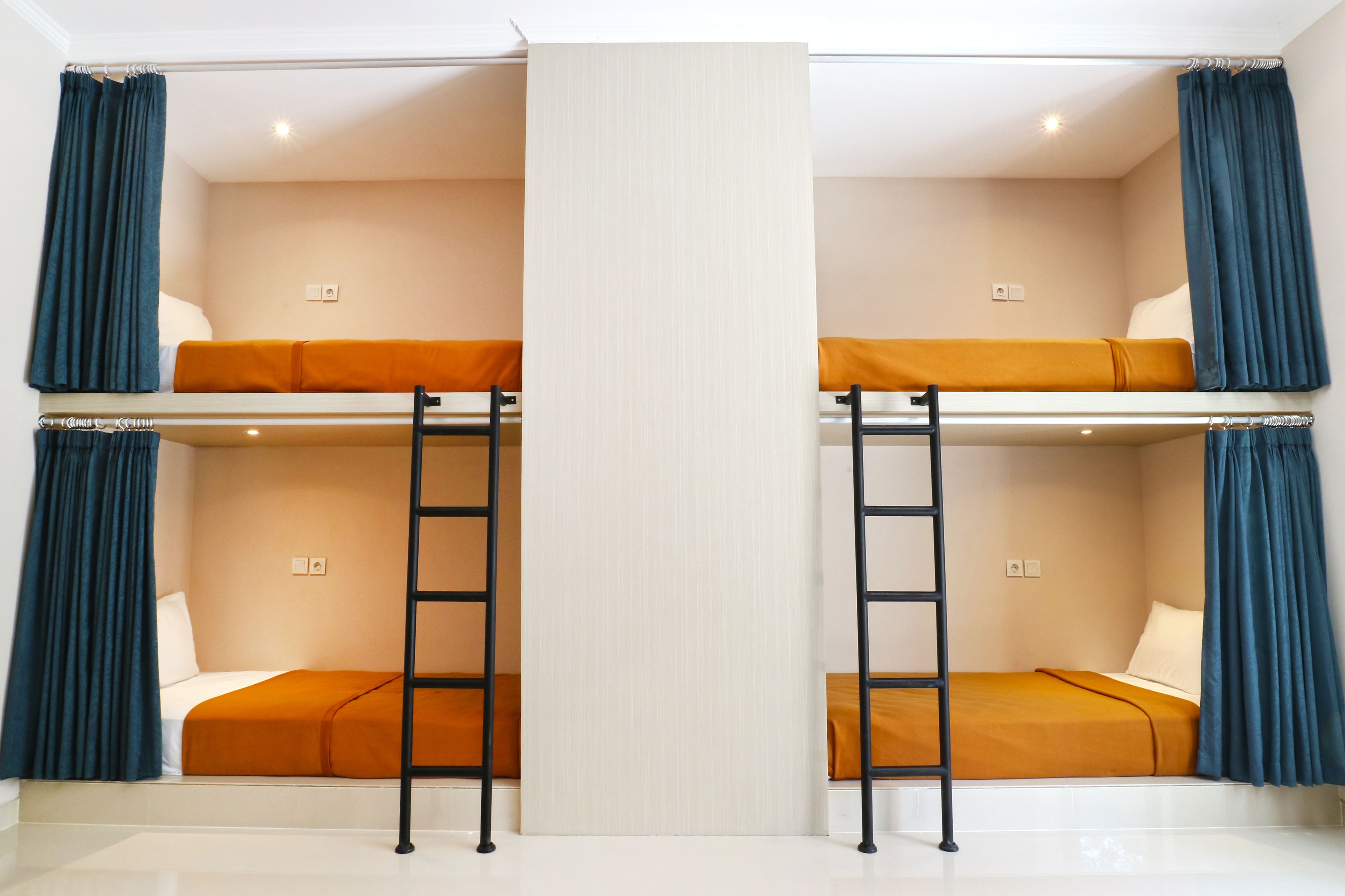 A room with two bunk beds, each with a ladder, and a central partition.