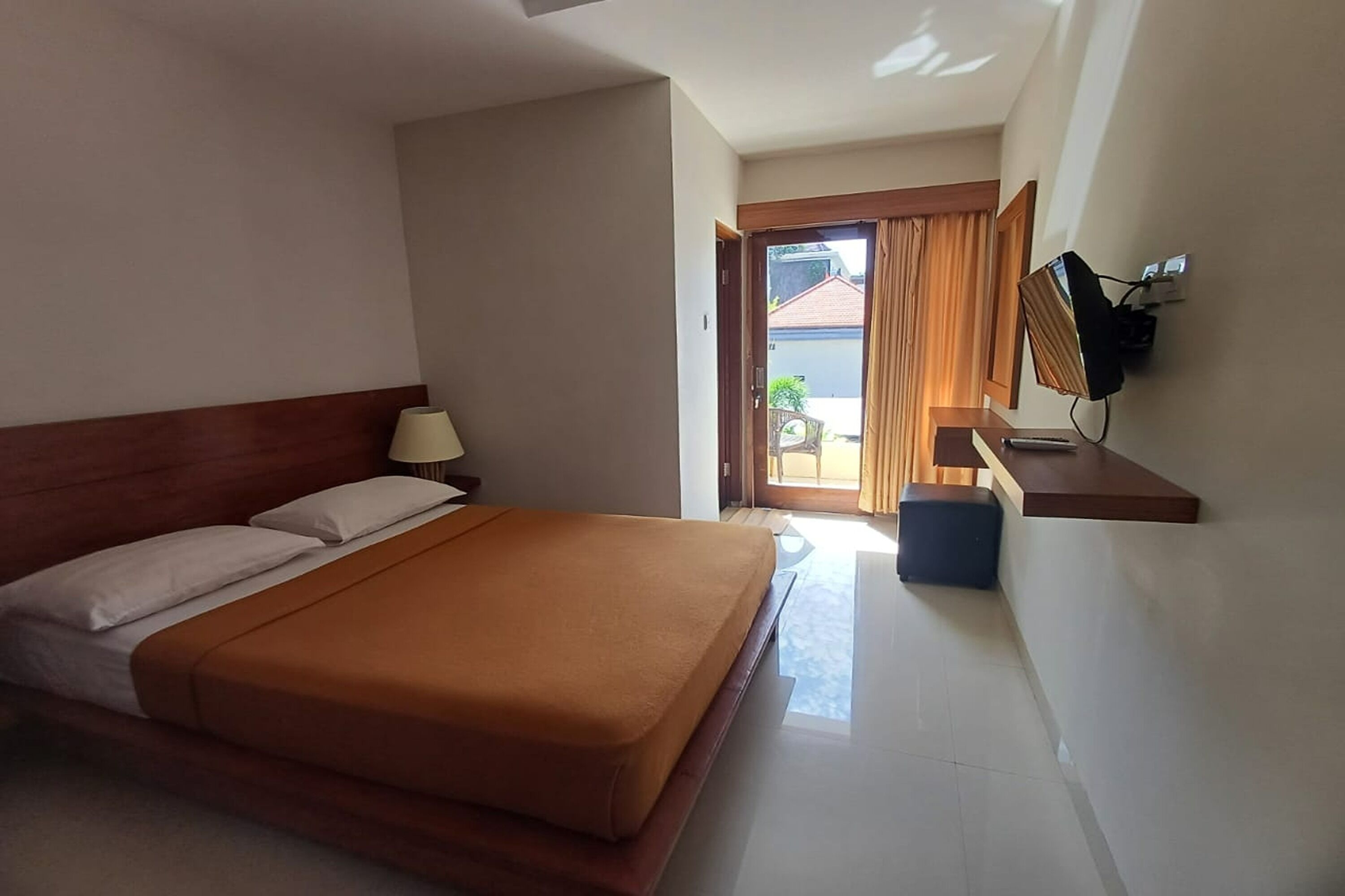 A hotel room with a bed, a desk, a lamp, and a television.