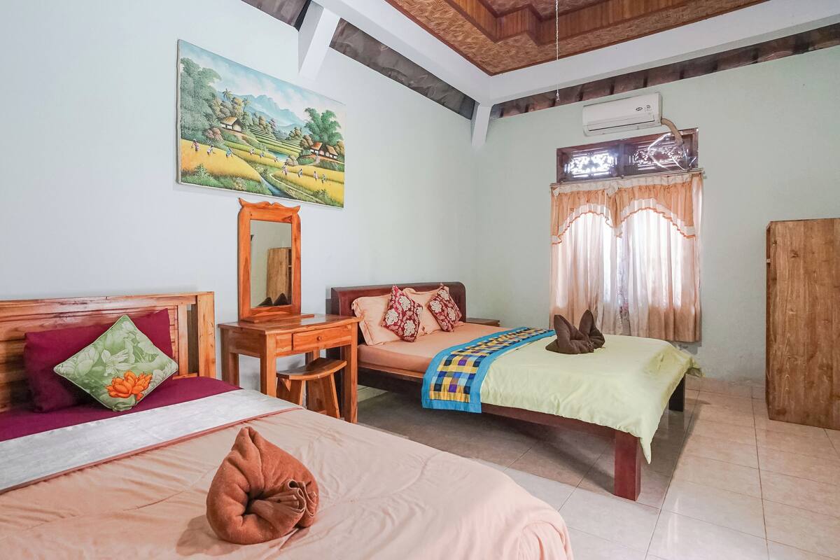 A bedroom with two beds, a desk, a mirror, and a painting on the wall.