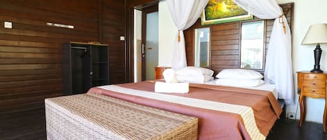 Un dormitorio con cama, un banco, una mesita de noche, una lámpara y un cuadro en la pared.