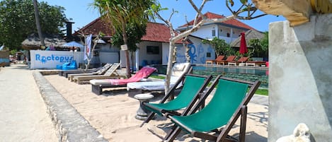 A beachside area with lounge chairs, a sign for 'Rooftop Villas', and a pool.