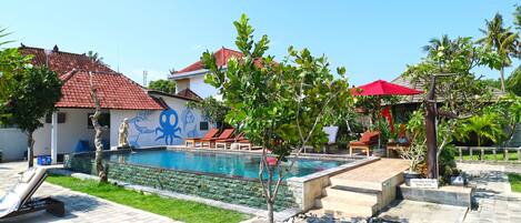 Zona de piscina con sillones de descanso, un árbol pequeño y un letrero que indica que es una piscina privada.