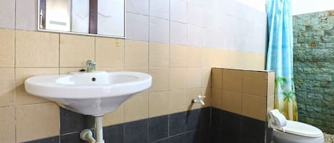 A bathroom with a white sink, a mirror, a toilet, and a blue trash bin.