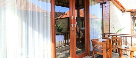 A wooden door with glass panels leading to a balcony with a tiled floor and a table with chairs.