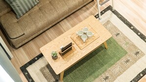 A room with a wooden coffee table, a sofa, a small plant, and a ladder. - Trip Pod Minoshima A (Fukuoka)