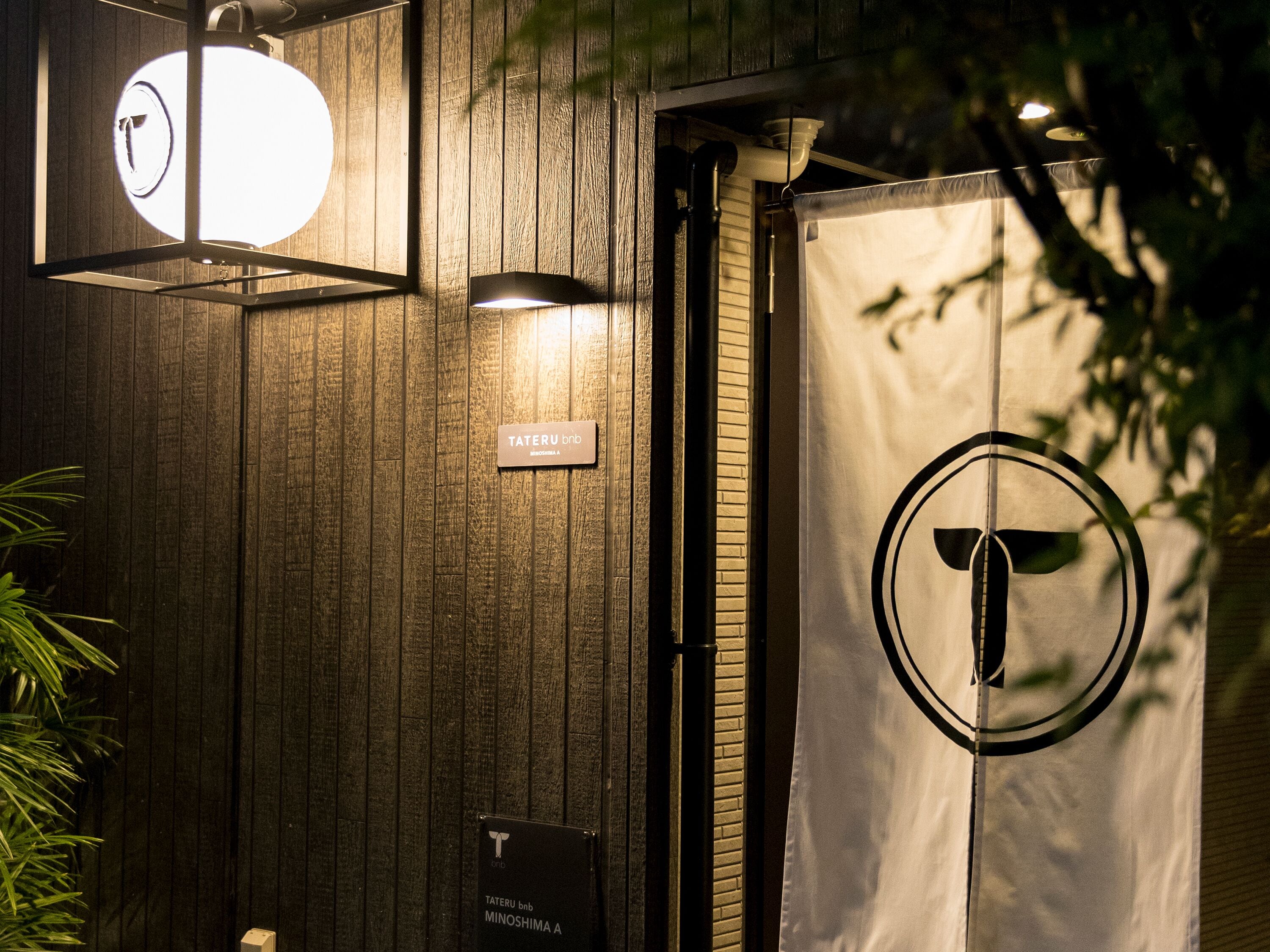 A wooden wall with a sign reading "Tateru bnb Minoshima A".