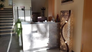 Un espace d’accueil doté d’un comptoir en marbre, d’une enseigne « BIENVENUE », d’une statue de Bouddha et d’un élément décoratif mural.