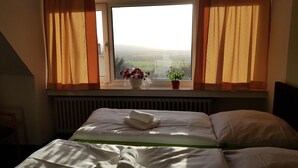 Une chambre d’hôtel avec un lit, une fenêtre avec des rideaux et une vue sur le paysage.