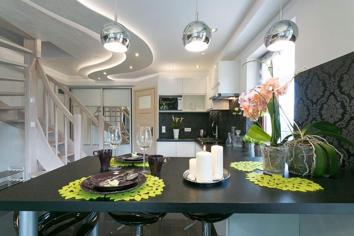 A modern kitchen with a central island, pendant lighting, and a staircase.