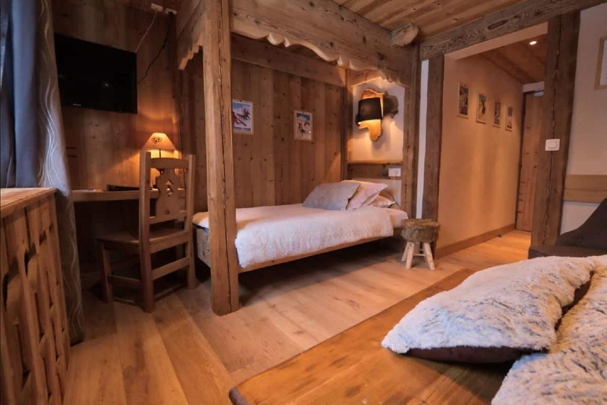 A cozy wooden room with a bed, a desk, and a chair.