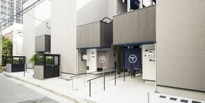 Un bâtiment moderne doté d’une entrée sécurisée par un portail, d’un escalier et d’une banderole bleue ornée d’un logo.