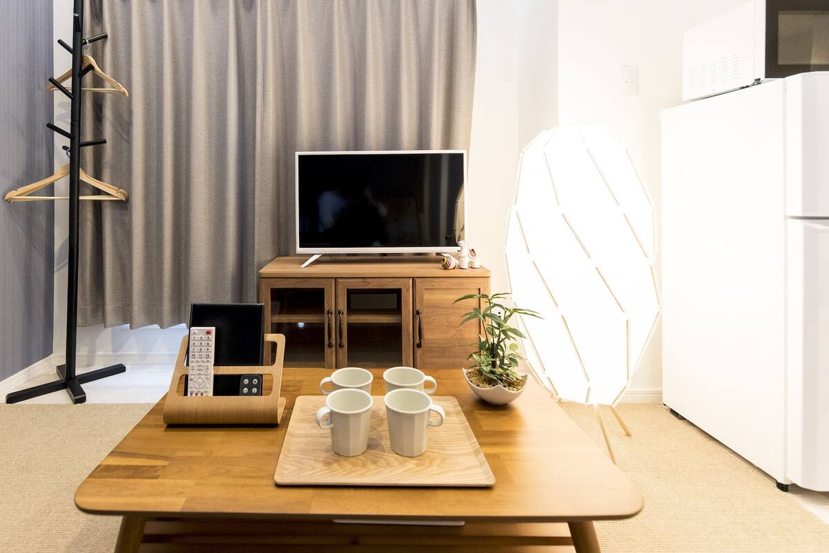 A modern living room with a wooden table, a TV, a cabinet, and a potted plant.