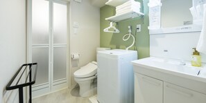 Une salle de bain équipée de toilettes, d’un lave-linge, d’un lavabo et d’un porte-serviettes.