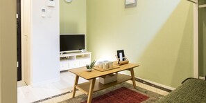 Une petite pièce avec une table en bois, un téléviseur et une petite plante.