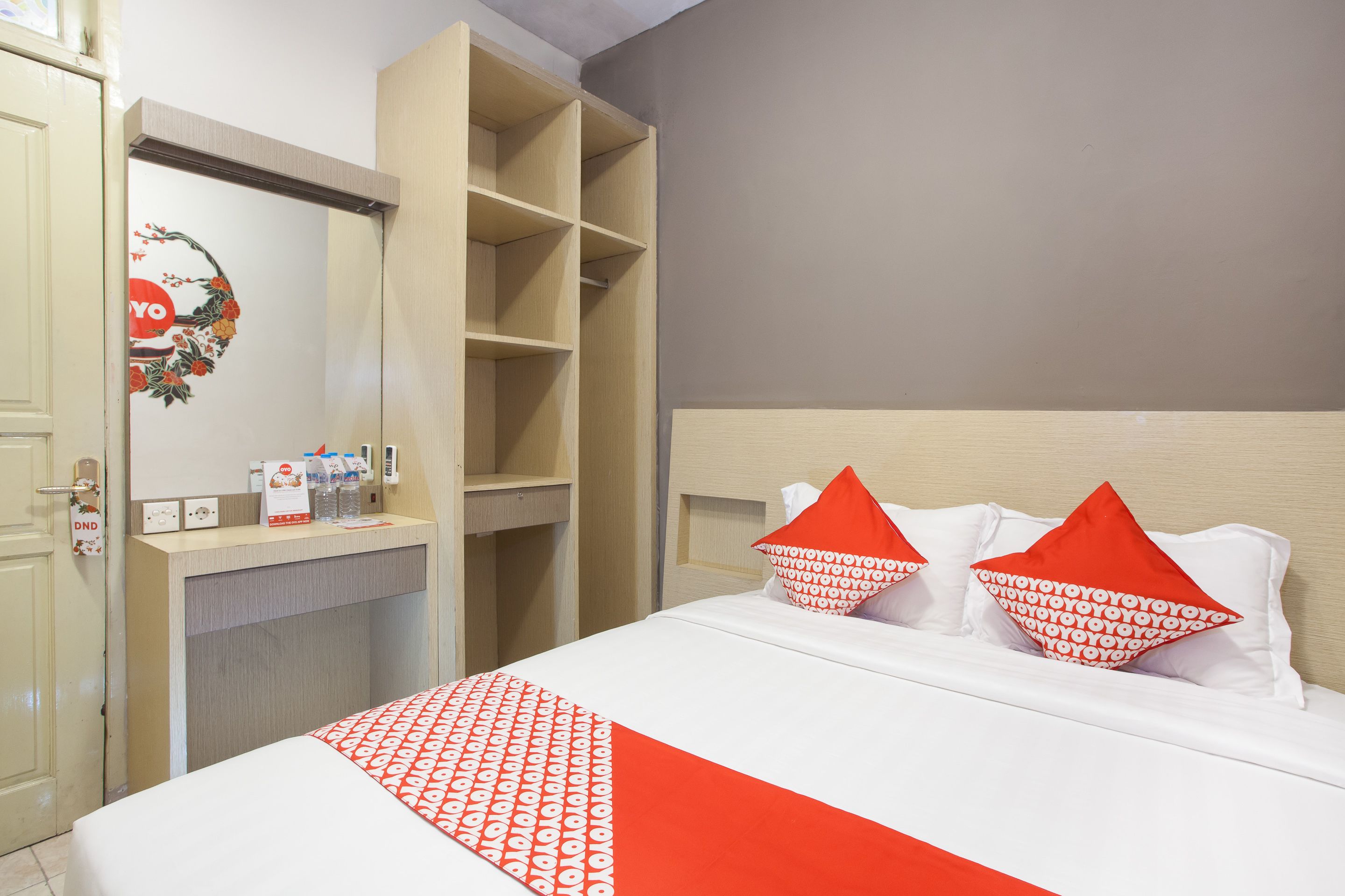 A hotel room with a bed, a wardrobe, and a desk with toiletries.
