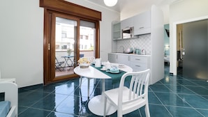 Una cocina moderna con armarios blancos, microondas y comedor con mesa y sillas blancas.