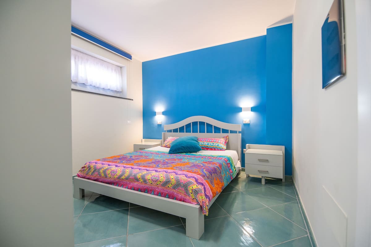 A bedroom with a bed, bedside tables, and a window with curtains.