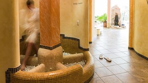 A spa area with a mosaic pool, a stone statue, and a tiled floor. - Jägerhof Geniesser & Wanderhotel (San Leonardo in Passiria)