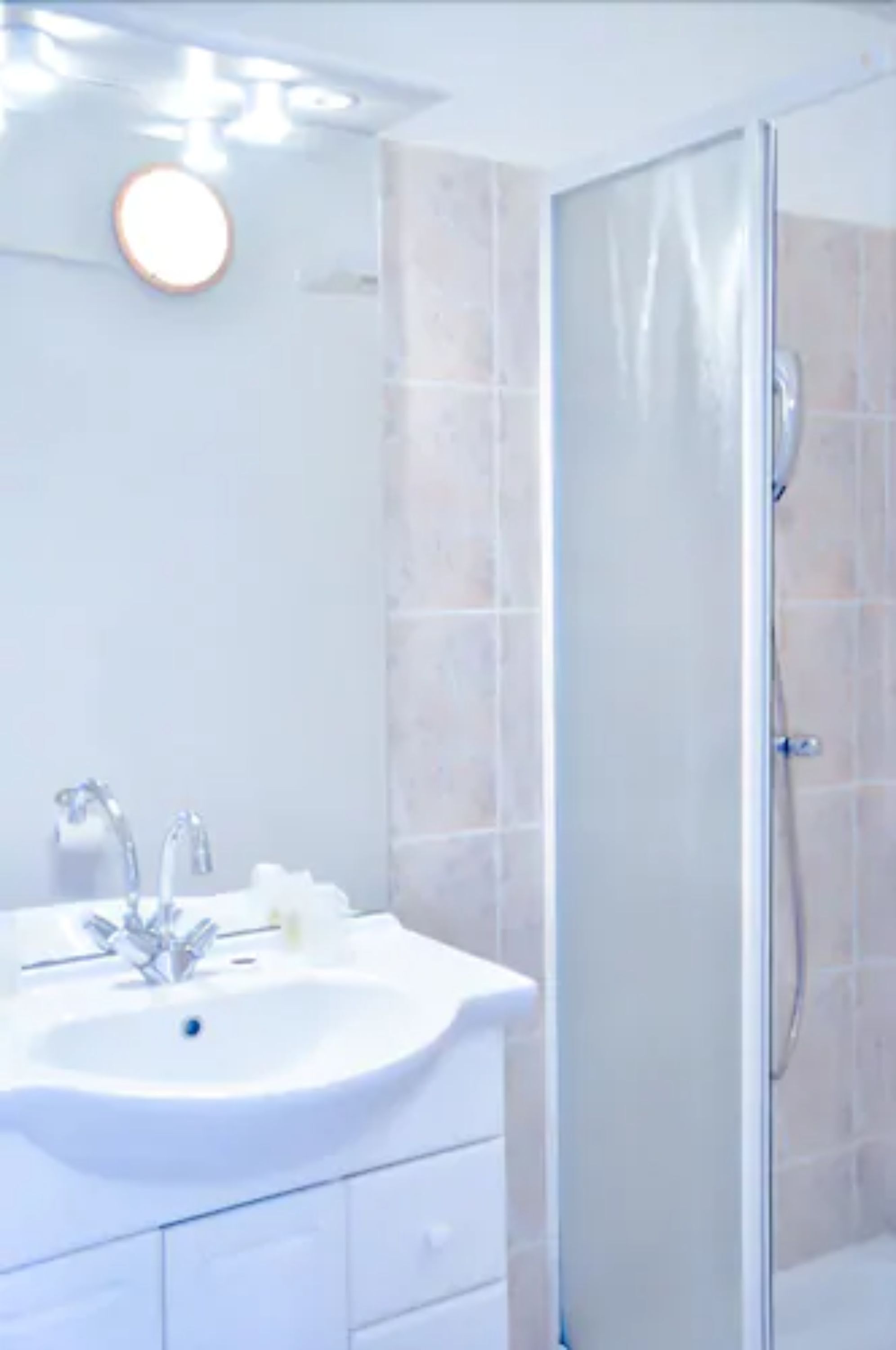 Een badkamer met een wit wastafelmeubel, een spiegel en een douchecabine van glas.