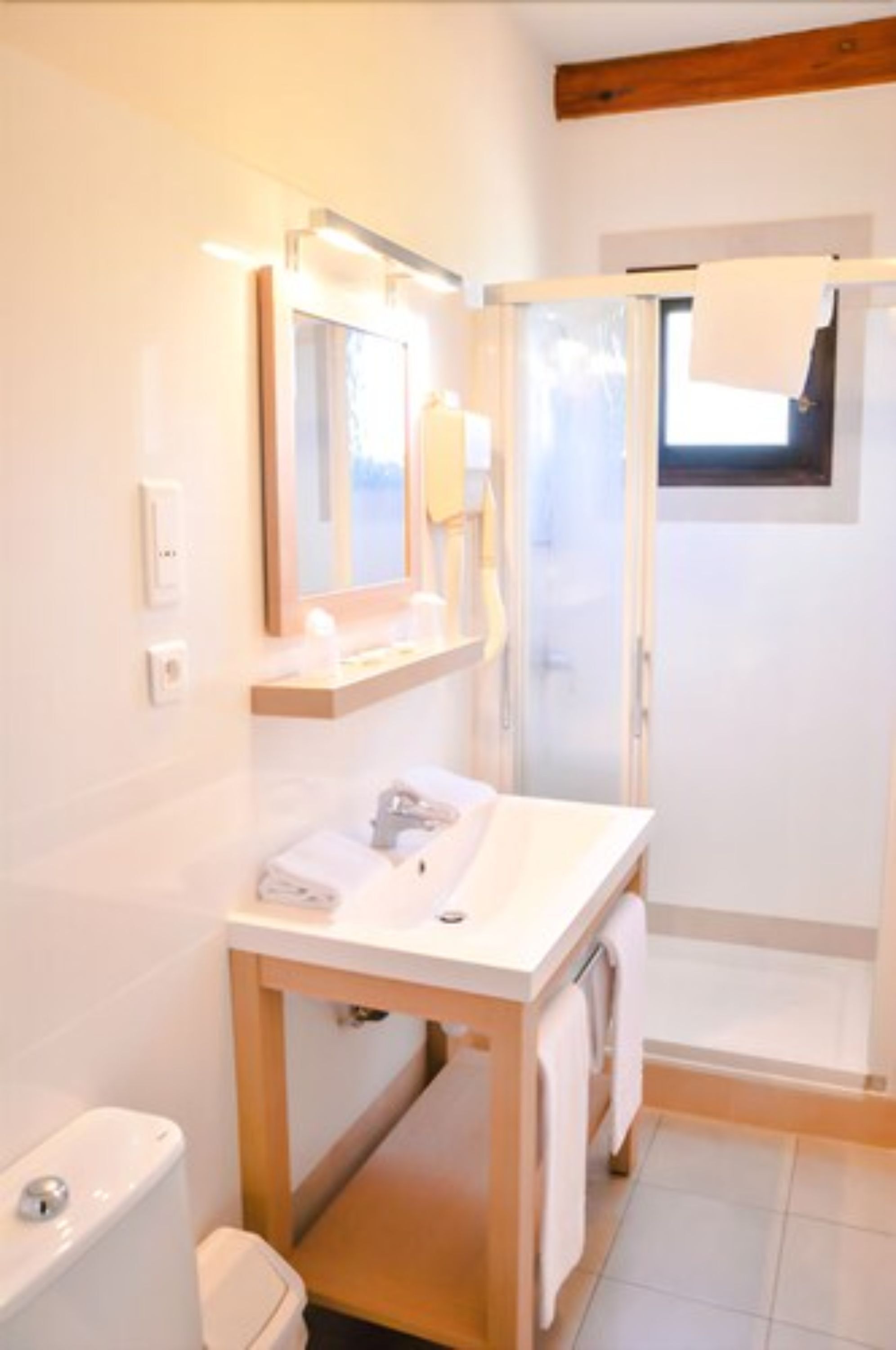 Une salle de bain moderne avec un lavabo blanc, un miroir et un espace douche.