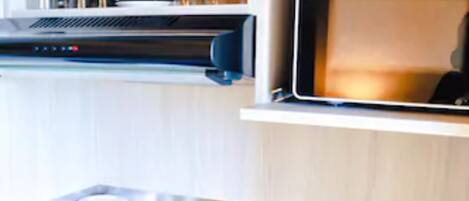 Una cocina compacta con estufa integrada, un lavabo y una repisa sobre la estufa con utensilios de cocina.