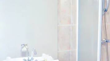 A bathroom with a white sink, mirror, and a glass shower enclosure.