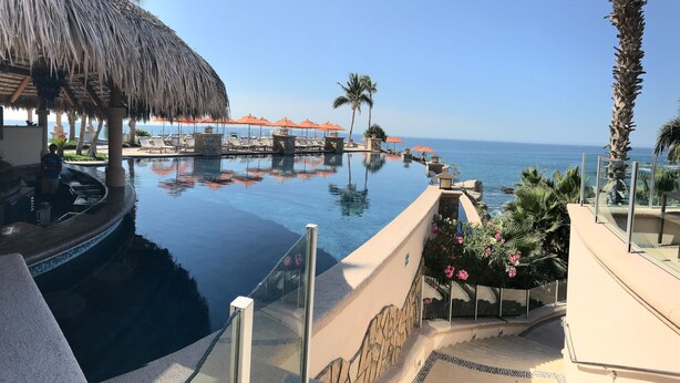 A infinity pool with a view of the ocean, lounge chairs, and a thatched roof structure. - Enjoy the Ocean View and take a stroll on the Stunning Private Beach (Cabo San Lucas)
