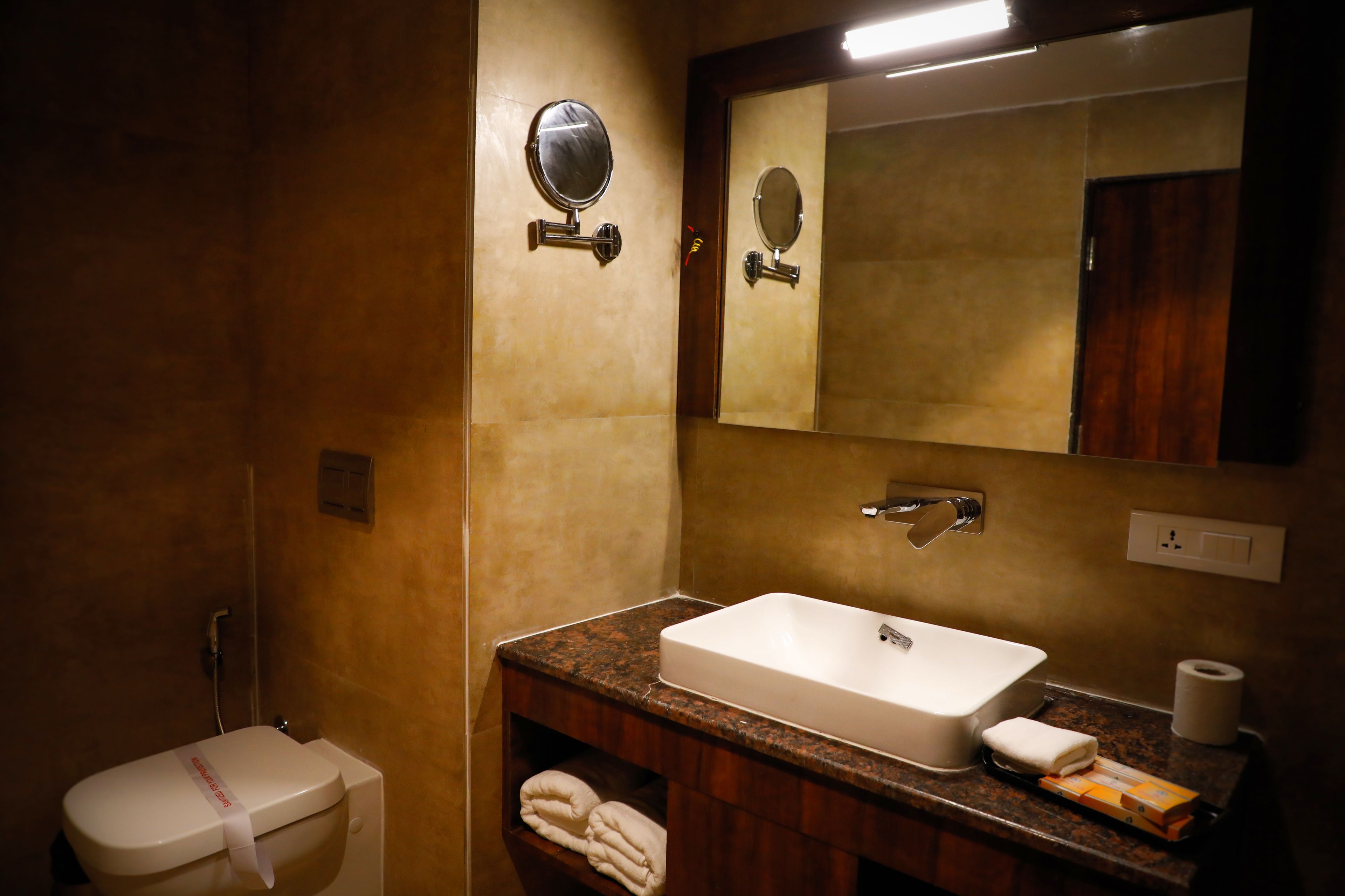 Un baño con lavamanos blanco, espejo, toallero y retrete.
