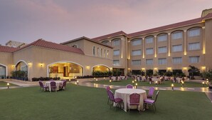 Un patio de hotel con mobiliario exterior y un edificio con múltiples ventanas y arcos.