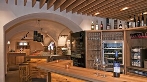 A bar area with wooden bar counters, stools, and a variety of wine bottles and glasses. - Hotel Gasthof Pockinger Hof (Pocking)
