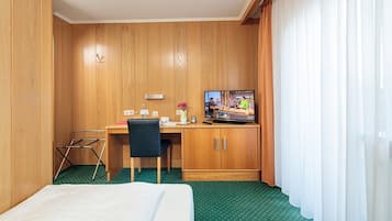 A hotel room with a bed, a desk with a chair, a television, and a wardrobe.