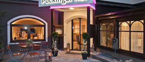 The exterior of Pockinger Hof hotel with a sign, outdoor seating area, and entrance.