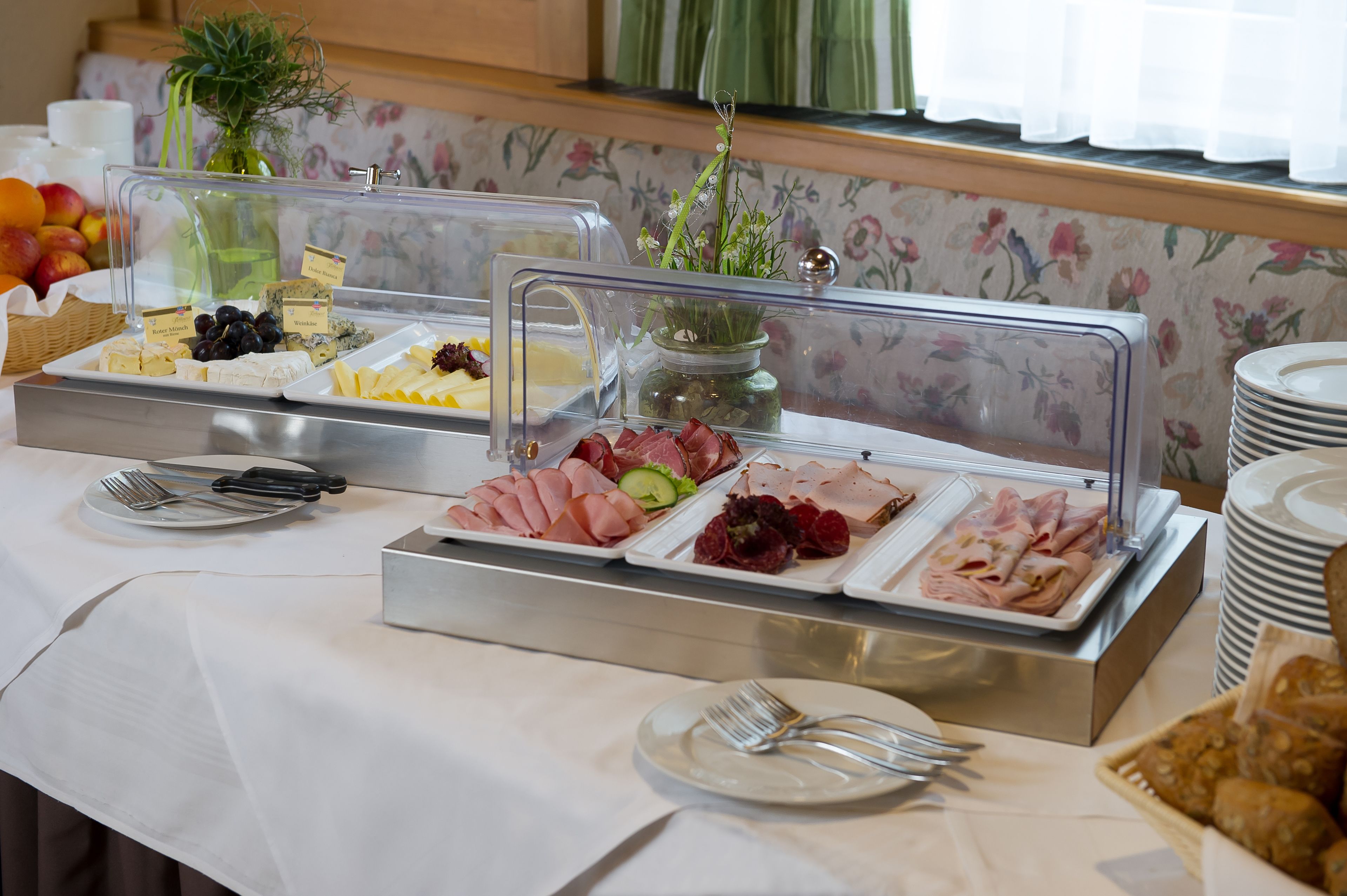 A buffet with various food items, including cheeses, meats, and fruits, displayed in clear containers.