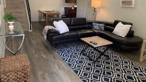 A modern living room with a black sectional sofa, a glass coffee table, and a patterned rug. - With snowbirds landing here you will be at home. City of Scottsdale: 2027801. (Scottsdale)