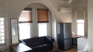 Ein gemütlicher Wohnbereich mit einer Couch, einem Esstisch, einem Kühlschrank und einem Bett.