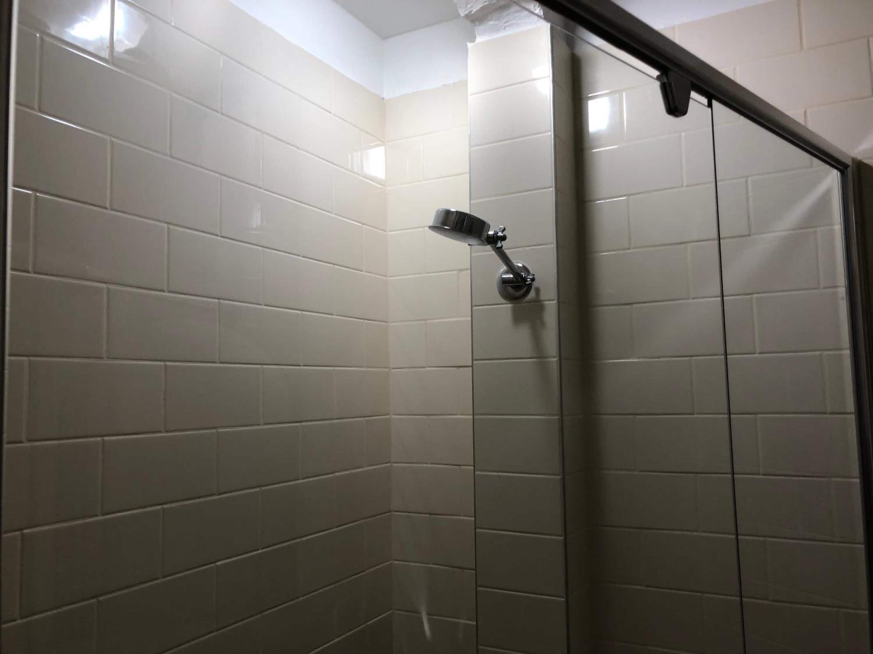 Zona de ducha con azulejos blancos y ducha de mano.