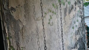 Pared desgastada con ladrillo visto y una cadena colgando.