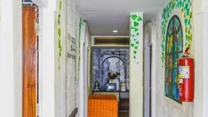 Un pasillo con suelo de madera, paredes blancas y adornos con hojas verdes.