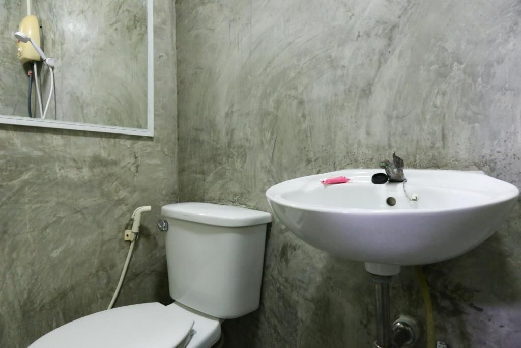 A bathroom with a white toilet, a white sink, and a mirror on the wall.