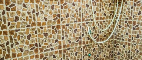 A bathroom with a mosaic tile wall, a toilet, and a shower area.
