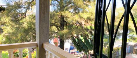 A balcony with a railing, a view of trees, and a glimpse of the surrounding area.