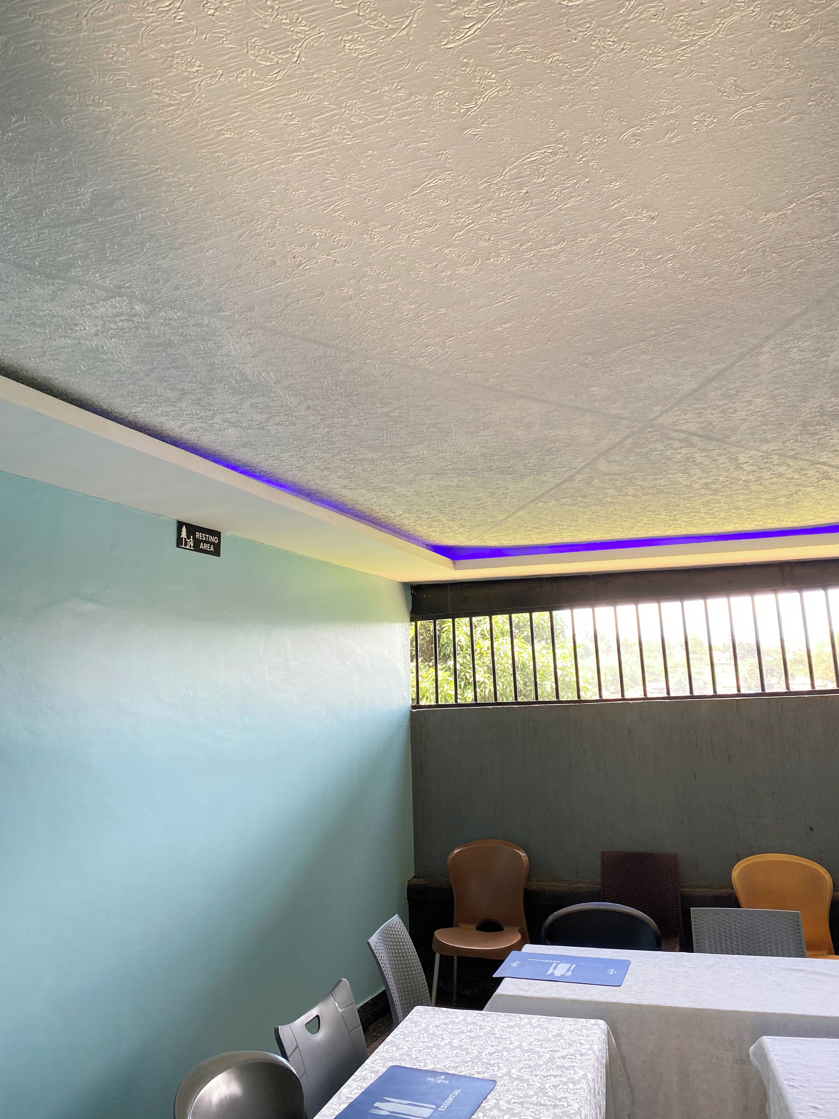 A room with a ceiling that has a textured pattern, a sign indicating a resting area, and a window with vertical bars.